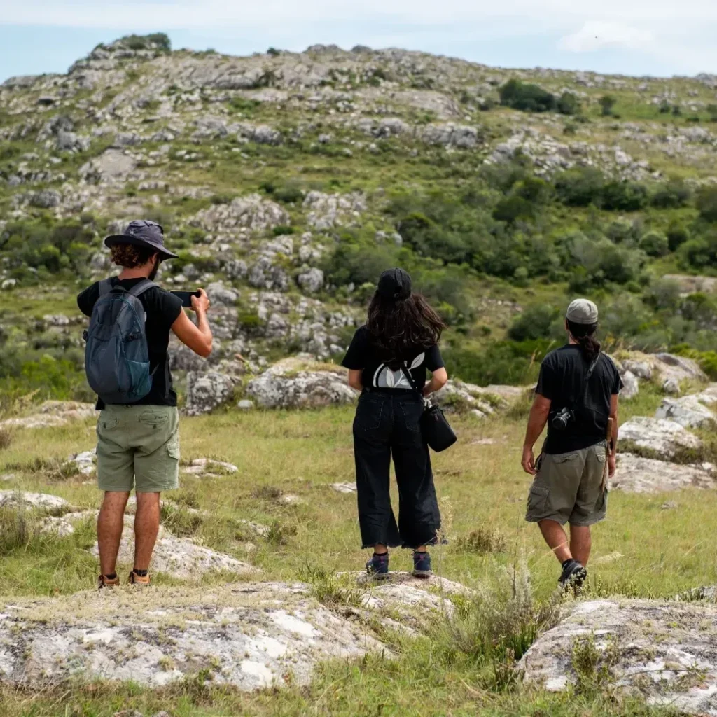 Personas caminando entre afloramientos de roca en el pastizal serrano de 7 Generaciones