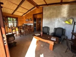 Estar con sillones y comedor de madera en la Cabaña Entre Lagos