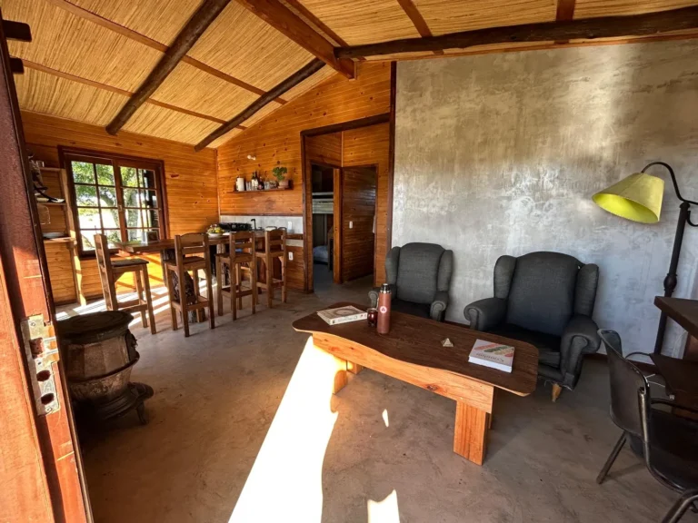 Estar con sillones y comedor de madera en la Cabaña Entre Lagos